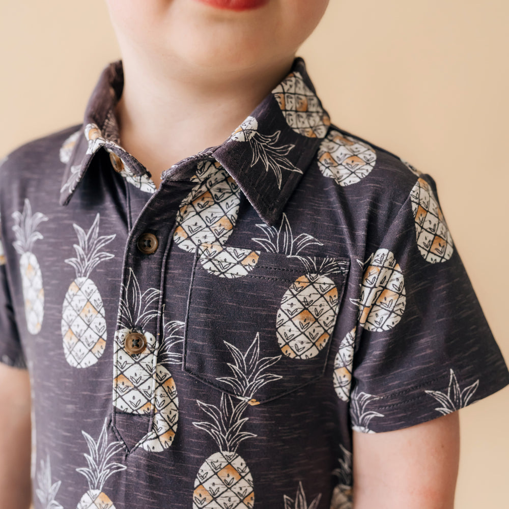 Close up image of a child wearing Sweet Paradise polo shorty romper detailing the chest pocket