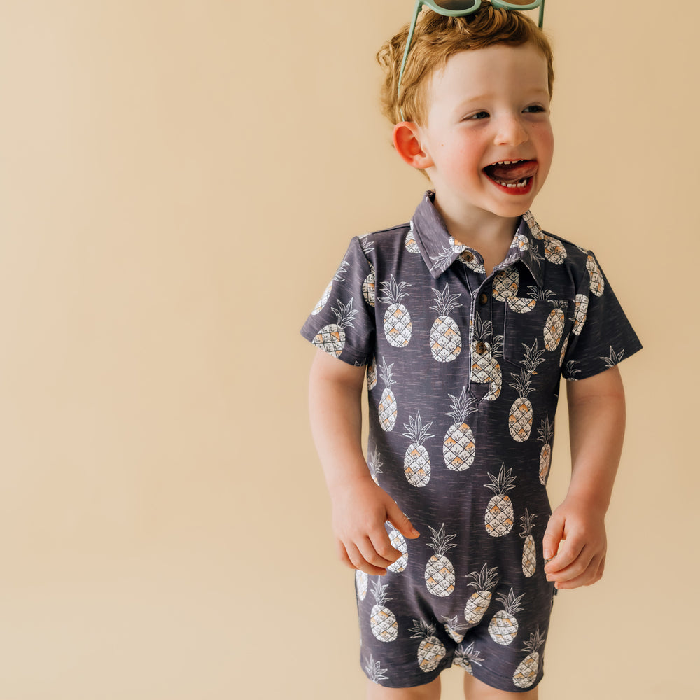 close up image of a child posing wearing Sweet Paradise polo shorty romper