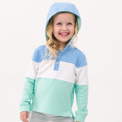 Close up image of a child wearing an Ocean Waves pullover hoodie with the hood up