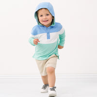 Child wearing an Ocean Waves pullover hoodie with the hood up and wearing coordinating Play shorts