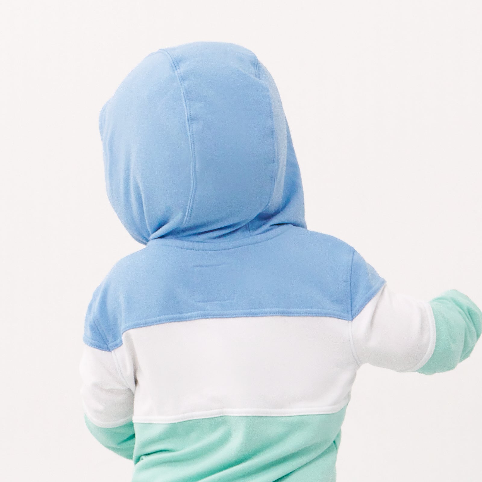 Back view image of a child wearing an Ocean Waves pullover hoodie with the hood up