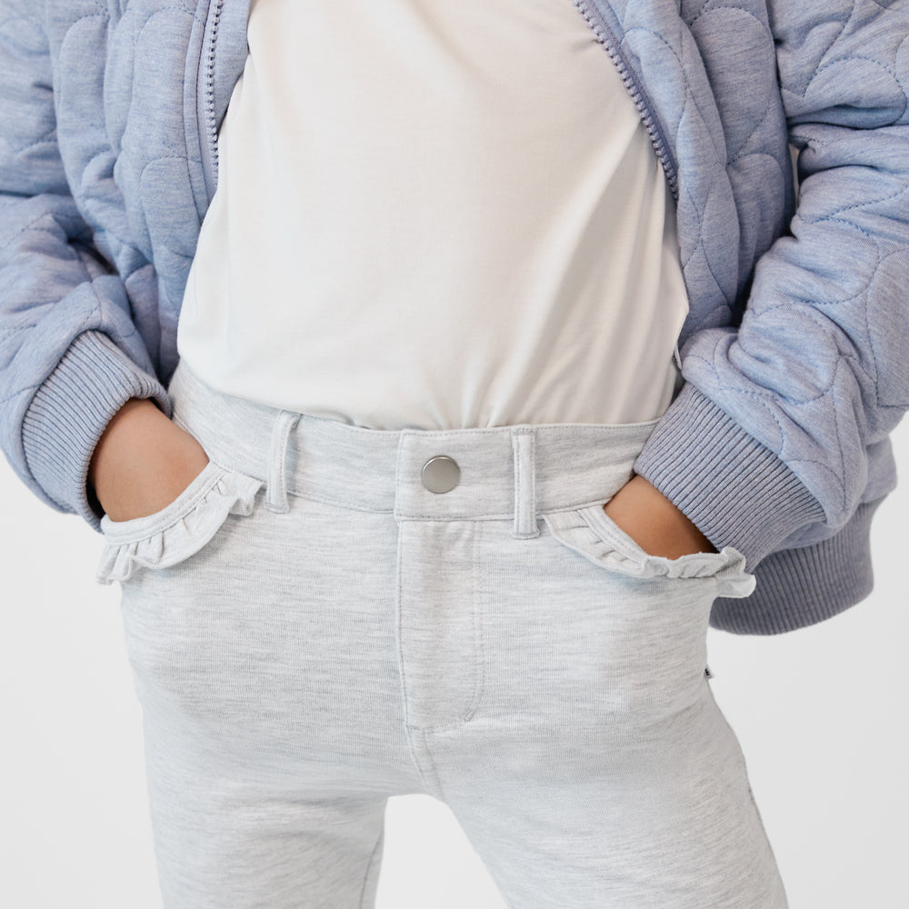 Close up of a child with their hands in the pockets of a Light Heather Gray Ruffle Heart Pocket Pants