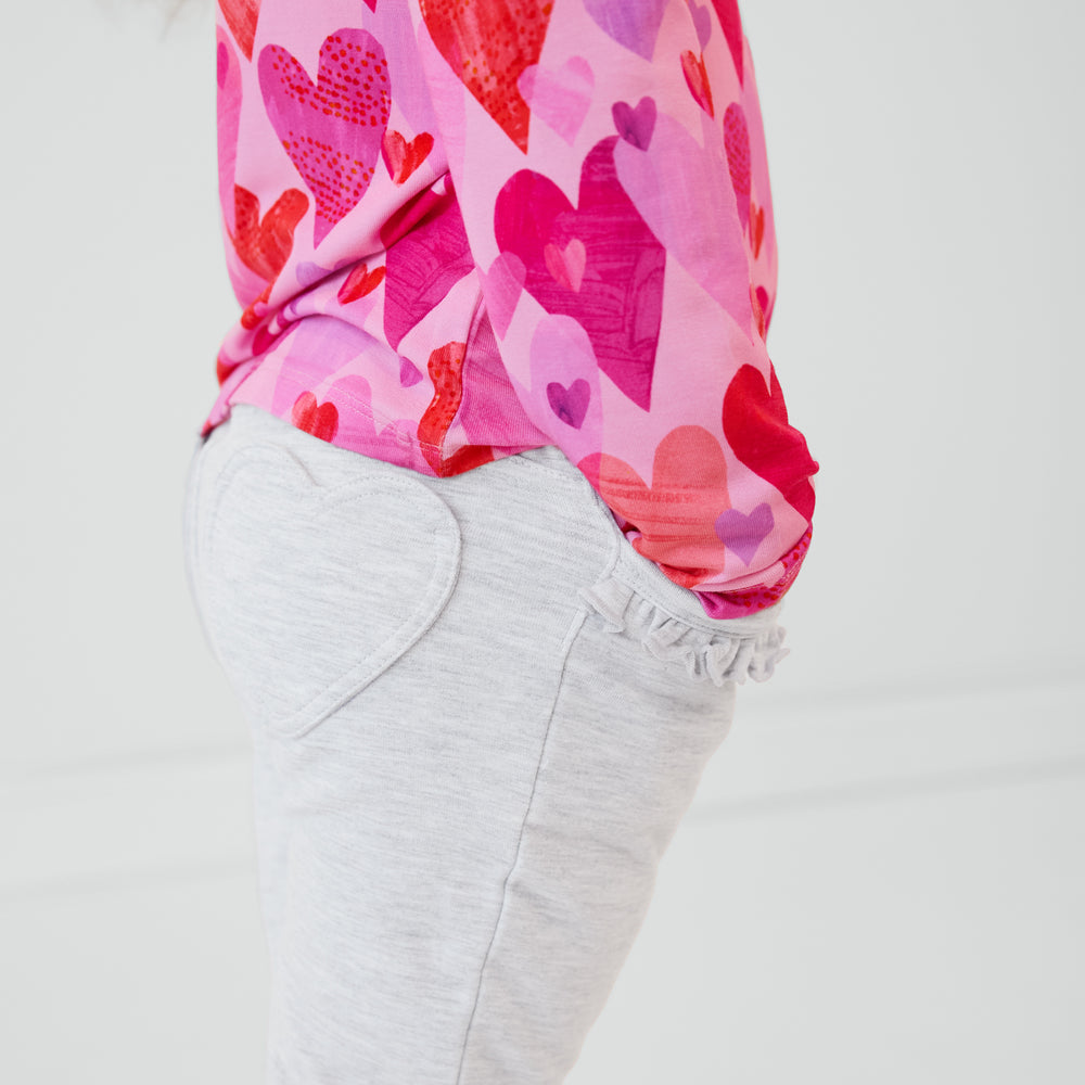 Close up side view of a child wearing Light Heather Gray Ruffle Heart Pocket Pants