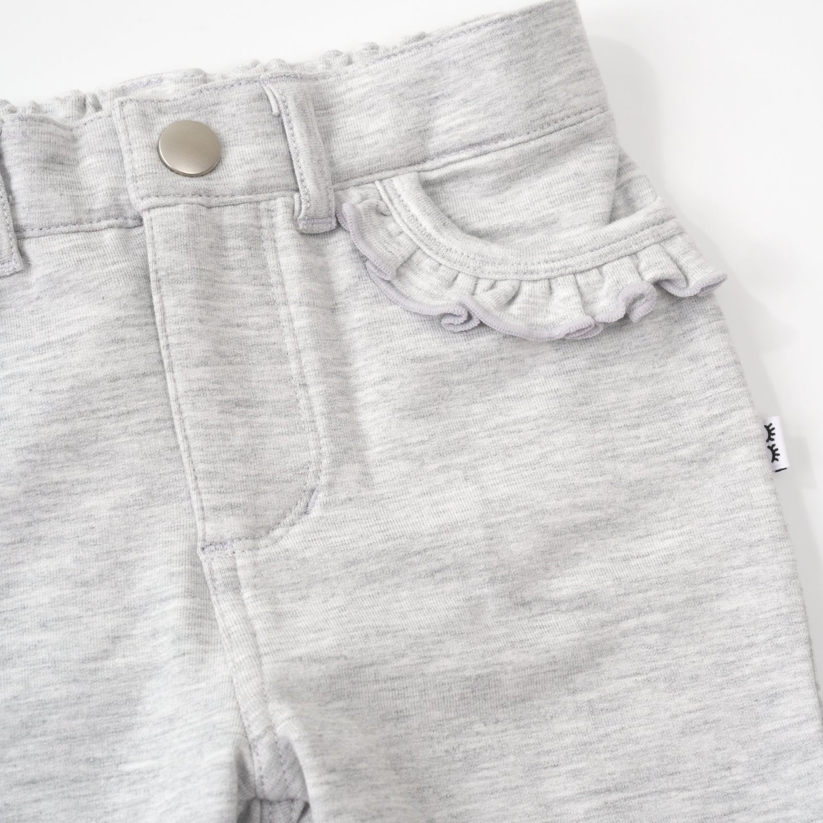 close up view of the ruffle pocket on a light heather gray ruffle heart pocket pant