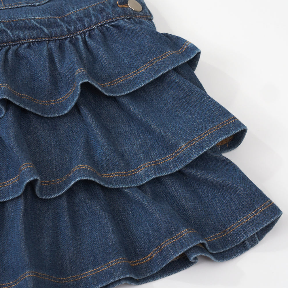 close up view of the tiered skirt on a midwash blue denim tiered skirt overall