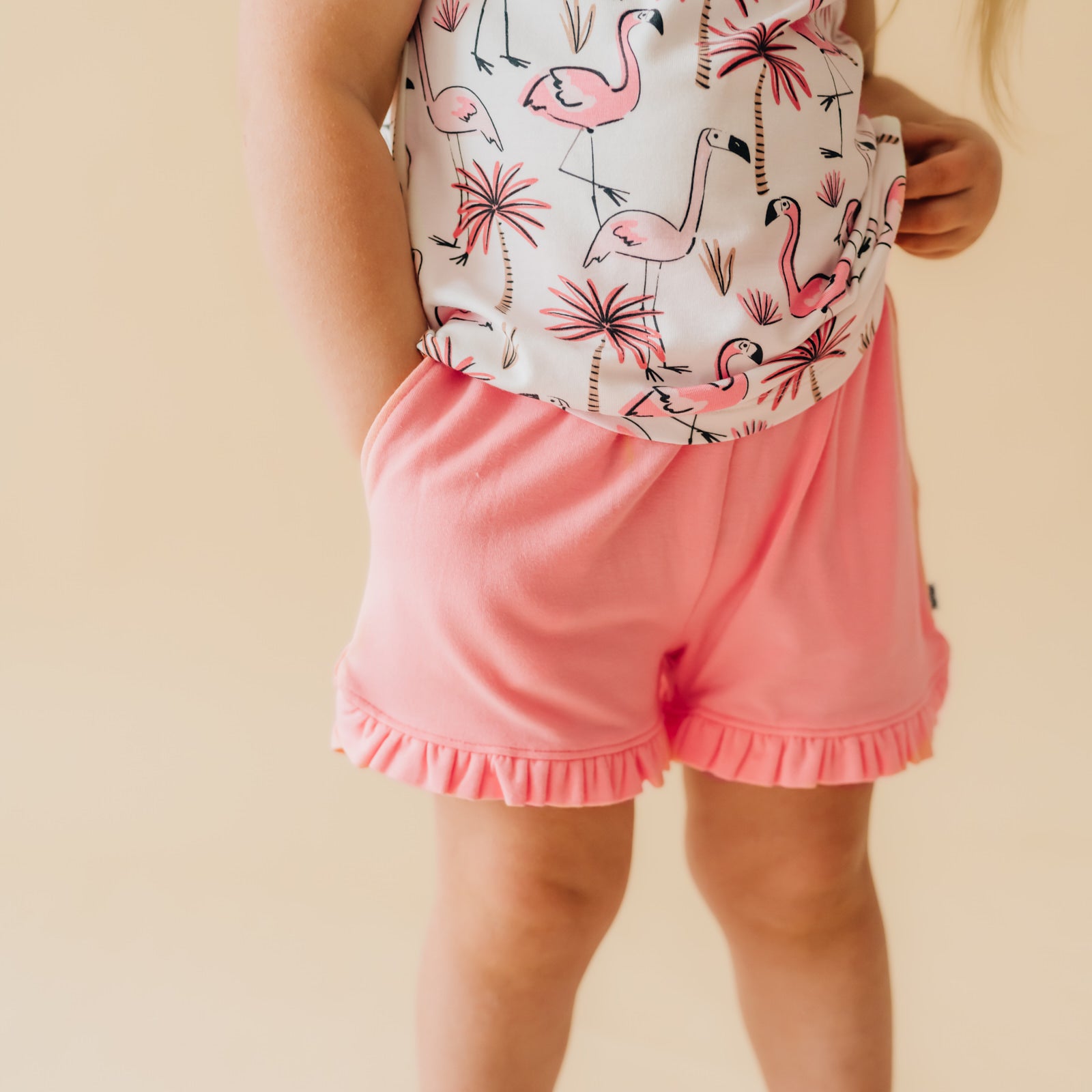 Close up image of a child wearing Coral ruffle shorts