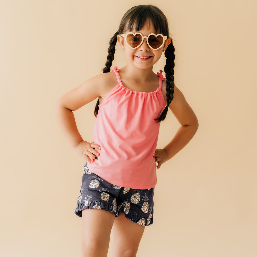 Child wearing a Coral Flowy Bow Strap tank paired with Sweet Paradise ruffle shorts