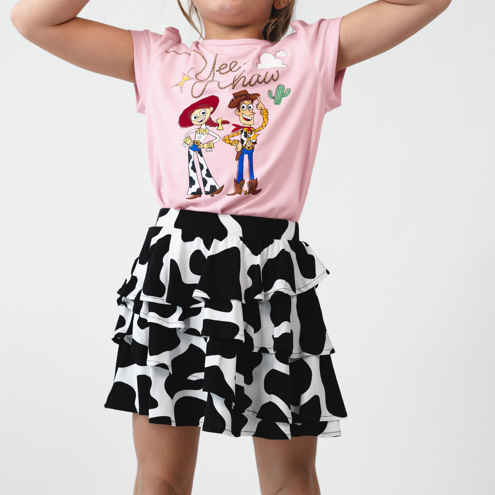 Close up view of a child wearing a Moo Crew Ruffle Skort and Disney & Pixar Jessie & Woody Puff Sleeve Tee