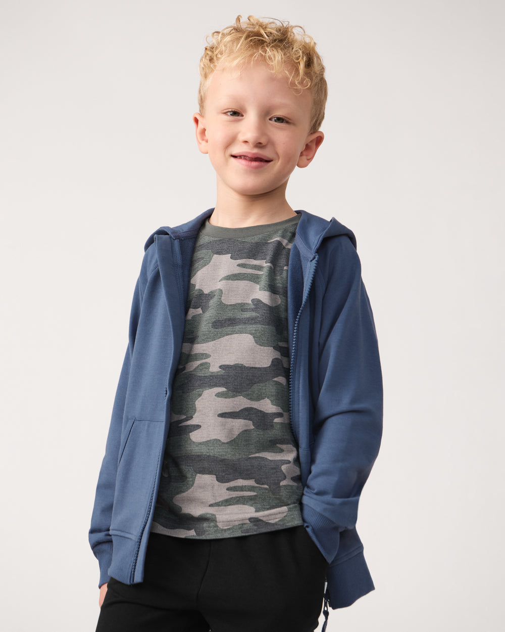 Boy wearing the Vintage Camo Short Sleeve Relaxed Tee layered under a navy hoodie