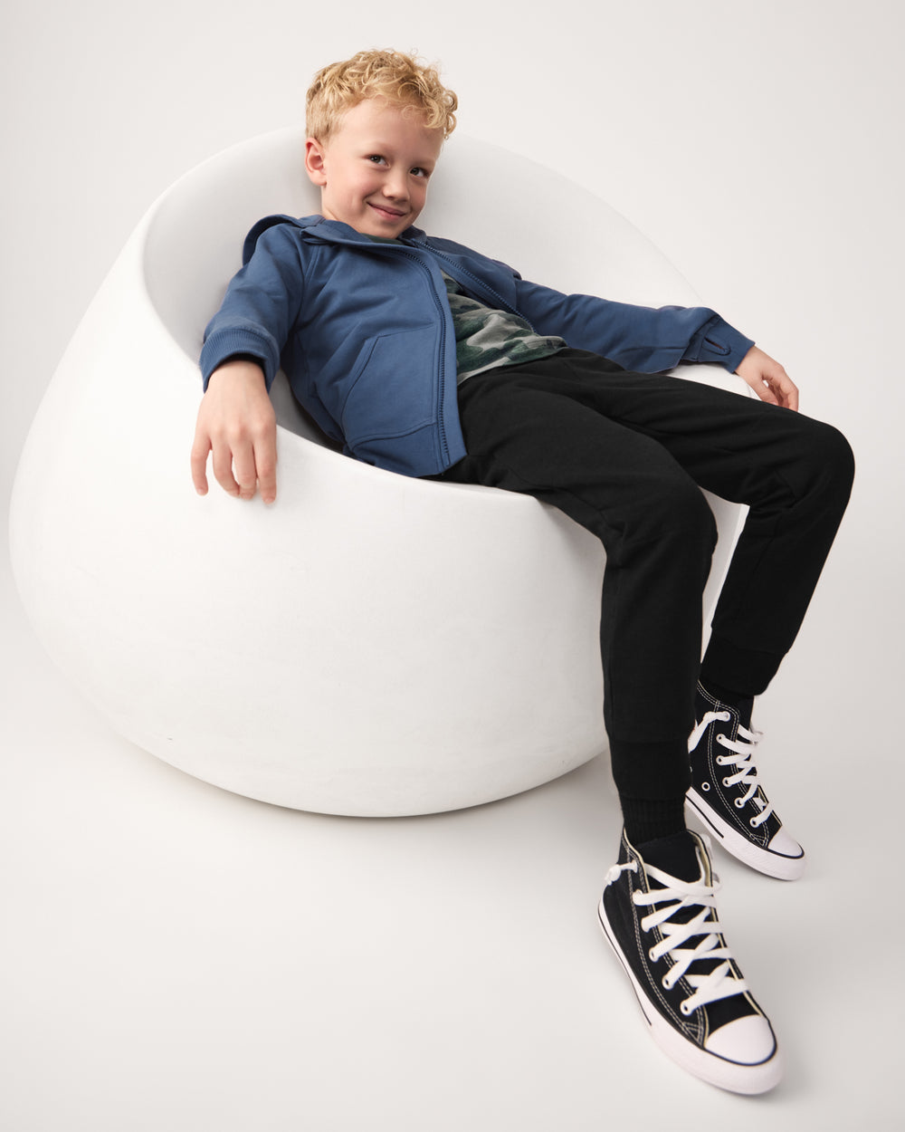 Child sitting on a white chair wearing the Black Jogger