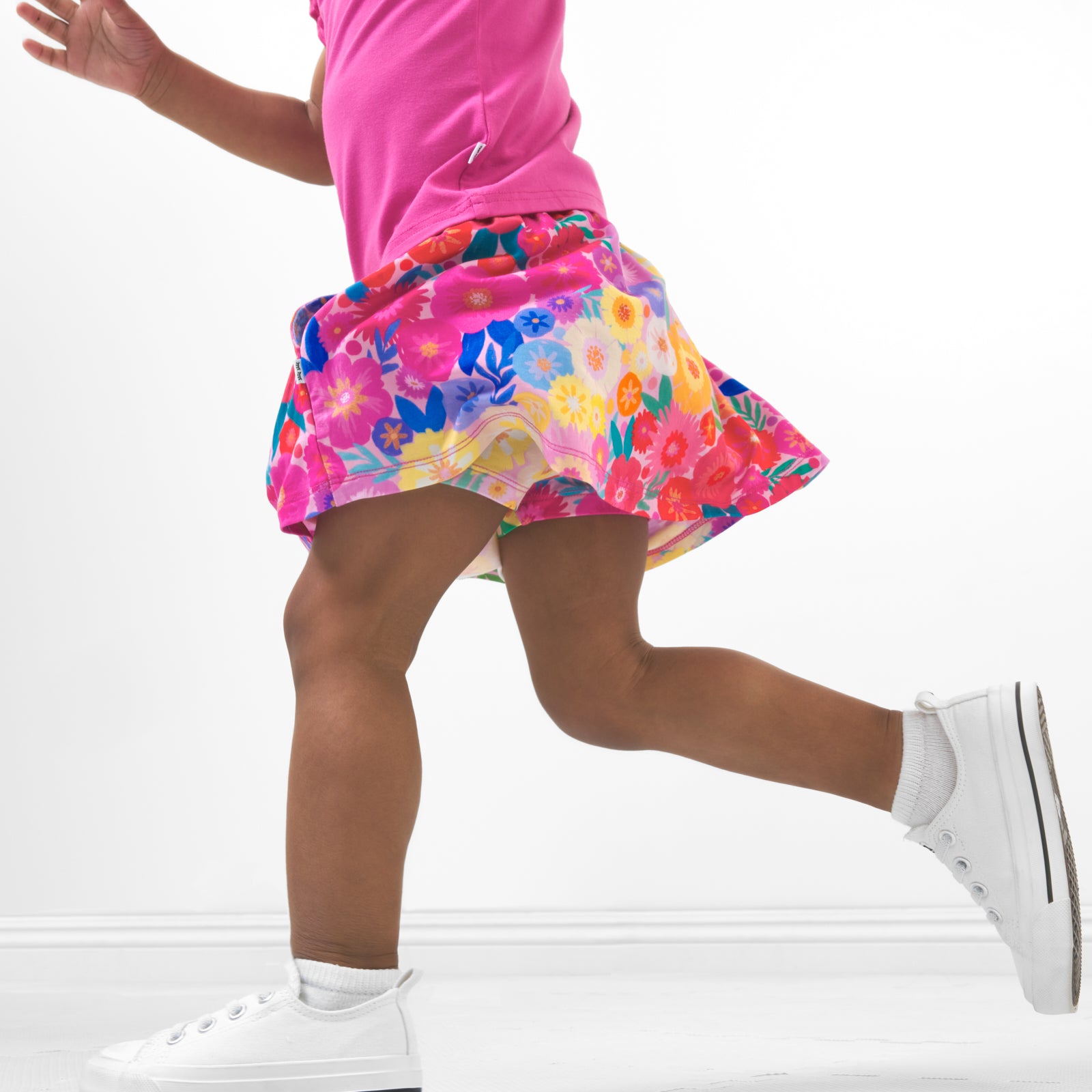 Alternate close up side view image of a child wearing a Rainbow Blooms skort and coordinating top