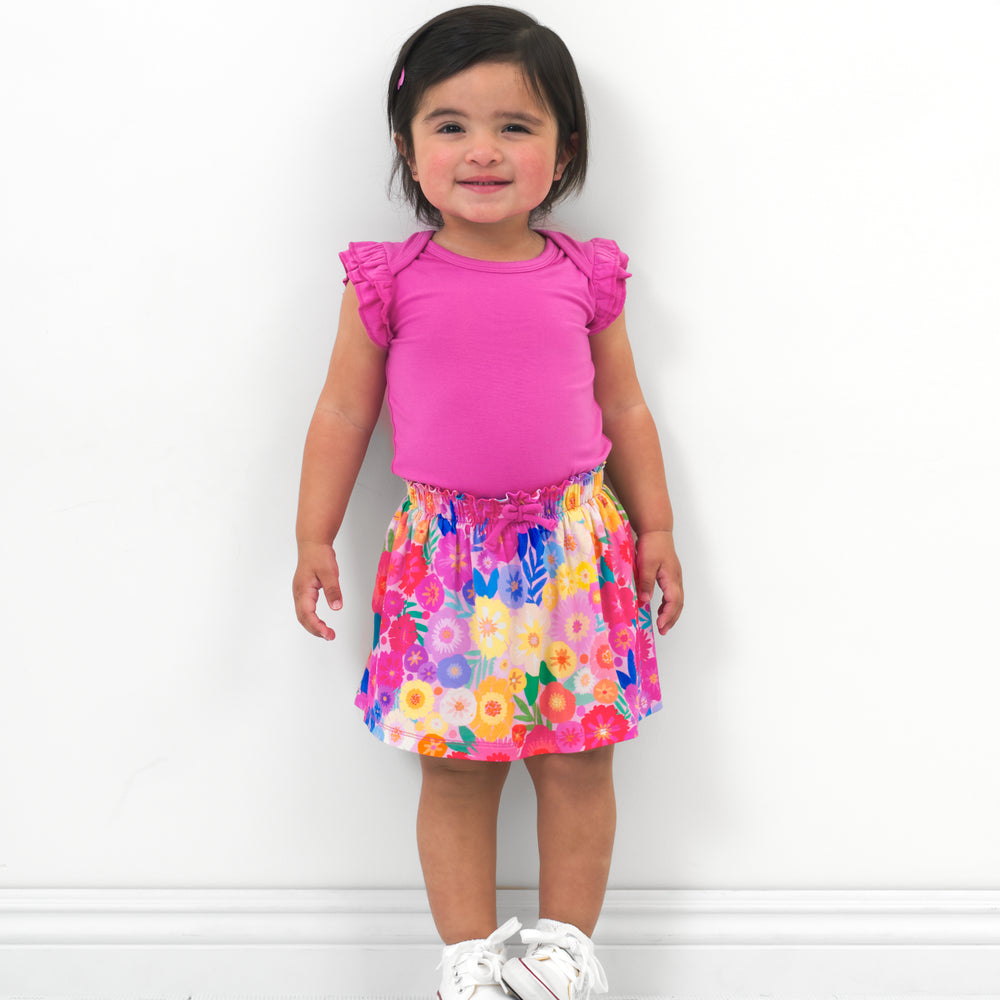 Child wearing a Rouge Pink Flutter Bodysuit paired with a Rainbow Flower Blooms skort