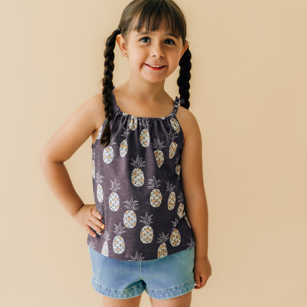 image of a child wearing a Sweet Paradise flowy bow strap tank paired with light blue denim shorts