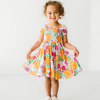 Child wearing a Beachy Blooms puff sleeve smocked dress holding out the sides of the dress