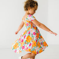 Side view image of a child spinning around wearing a Beachy Blooms puff sleeve smocked dress