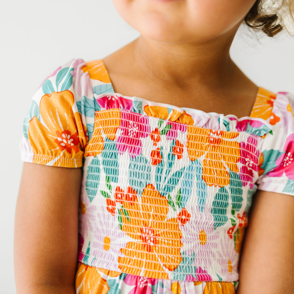 Close up image of a child wearing a Beachy Blooms puff sleeve smocked dress