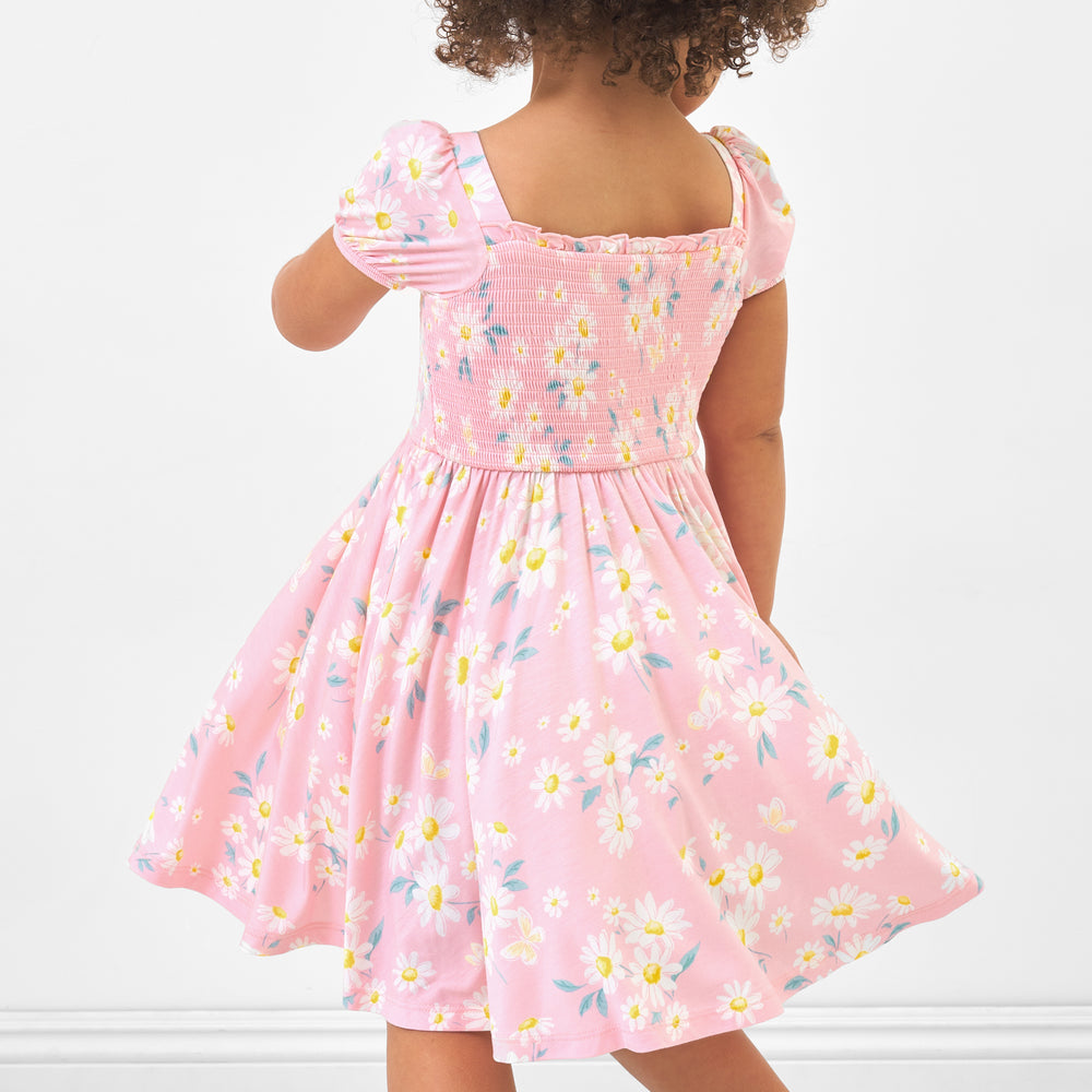 Back view image of a child wearing a Rosy Meadow puff sleeve smocked dress