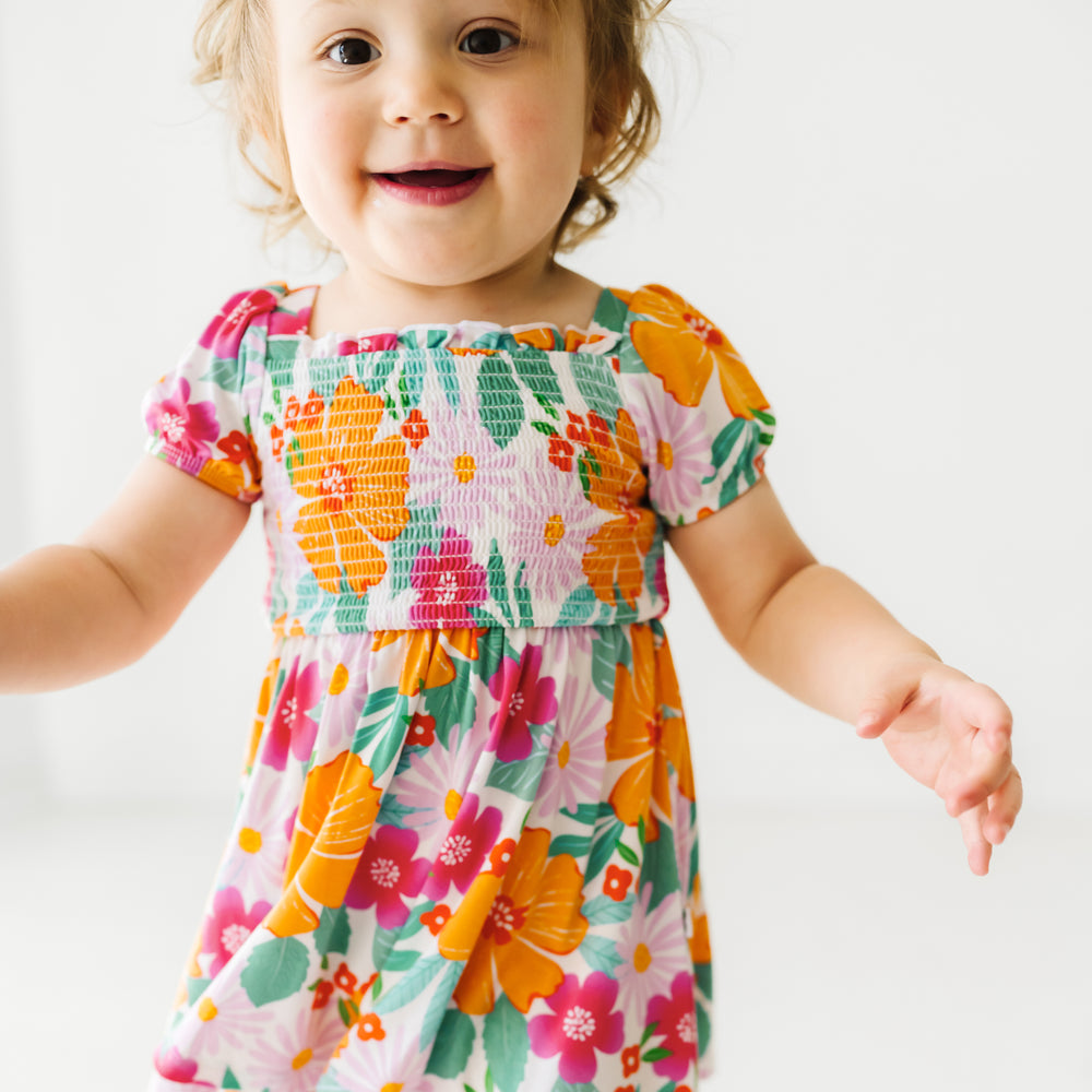 Close up image of a child wearing a Beachy Blooms puff sleeve smocked dress with bloomer