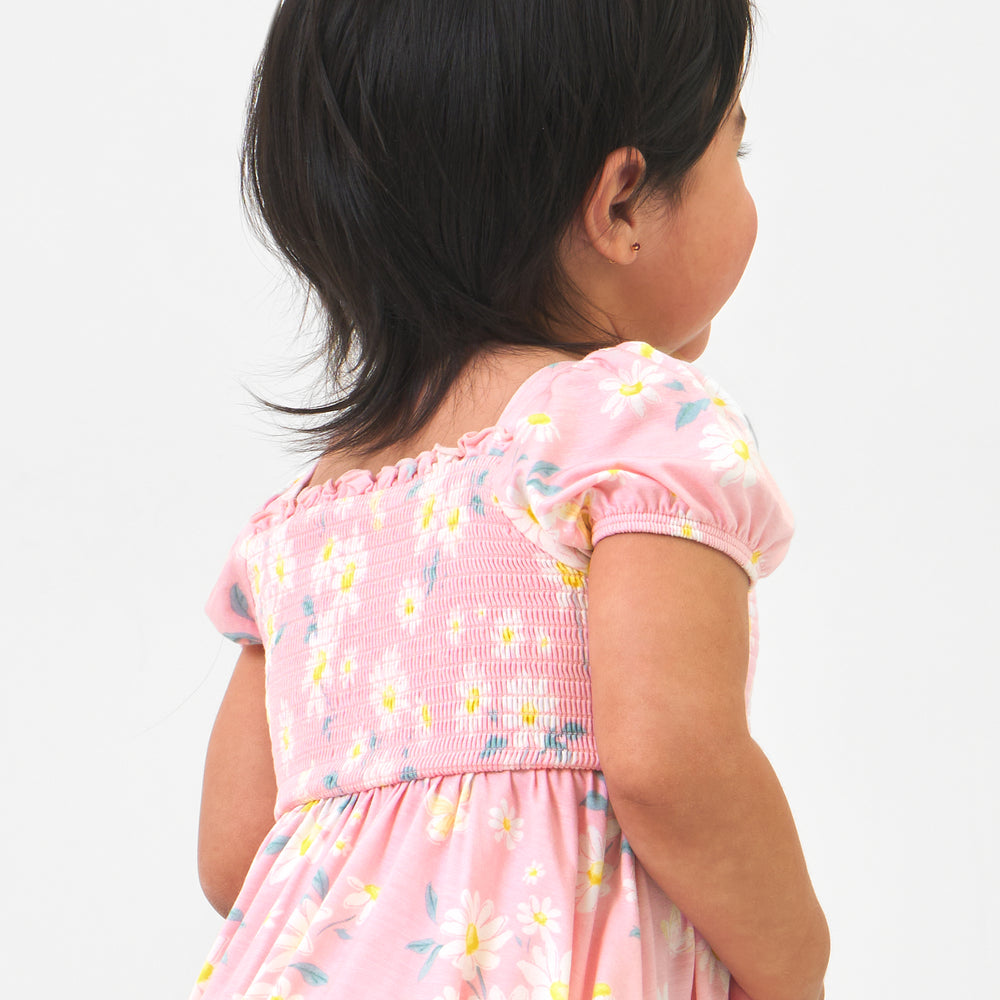 Back view image of a child wearing a Rosy Meadow puff sleeve smocked dress with bloomer