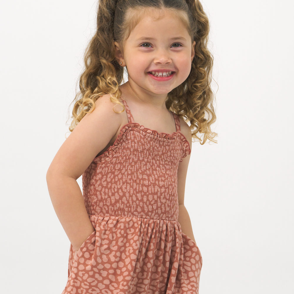 Close up image of a child wearing a Desert Leopard tank smocked dress