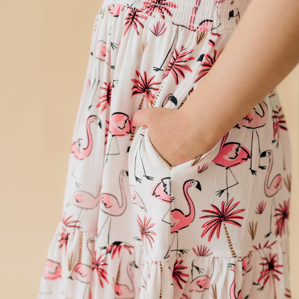 Close up image of a child wearing a Pink Palms tank smocked dress focusing on the dress's pockets