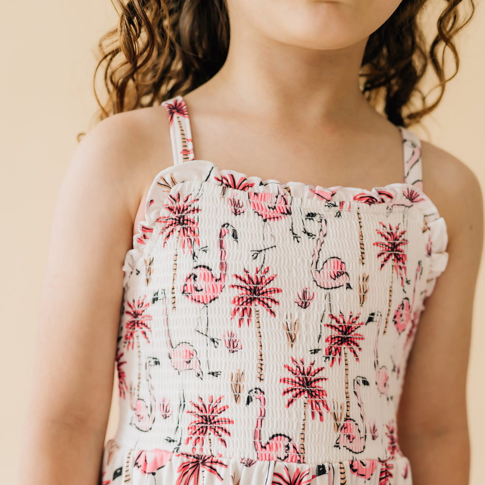 Close up image of a child wearing a Pink Palms tank smocked dress with a close up on the smocked front