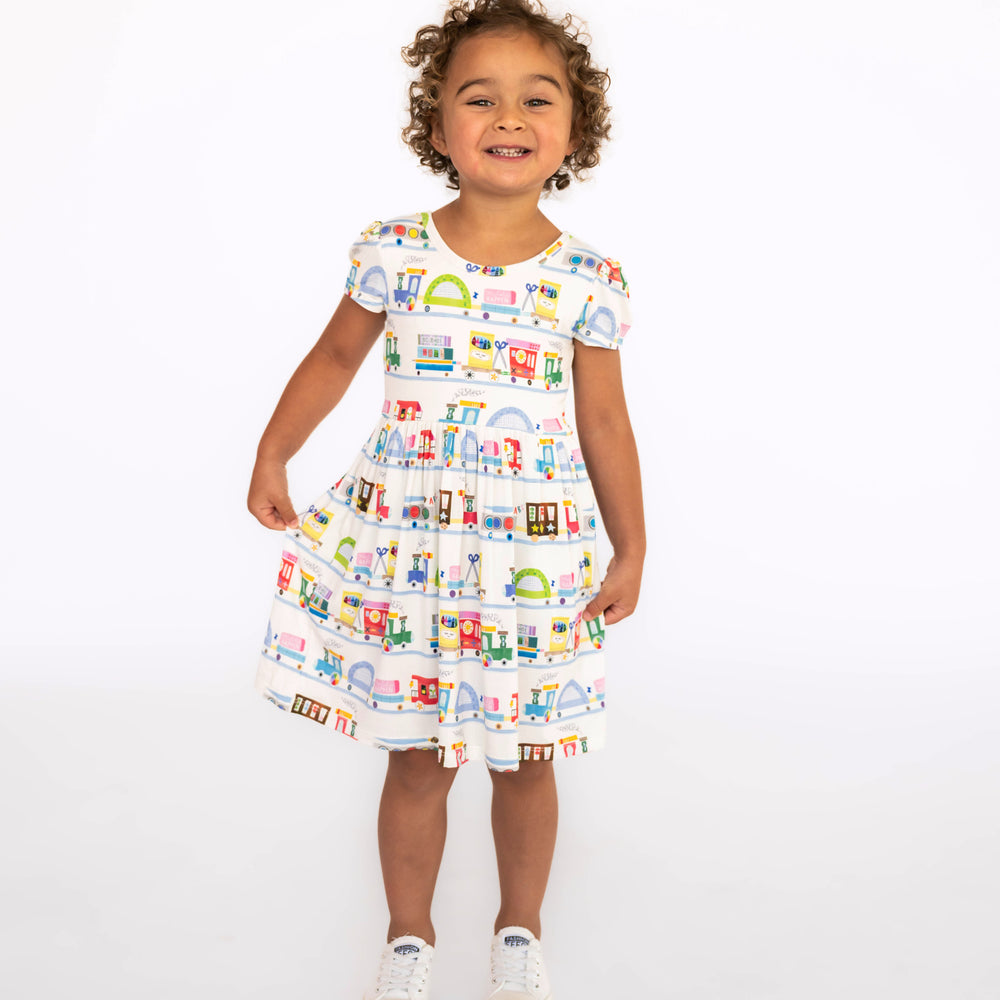 Child standing while wearing the Education Express Skater Dress