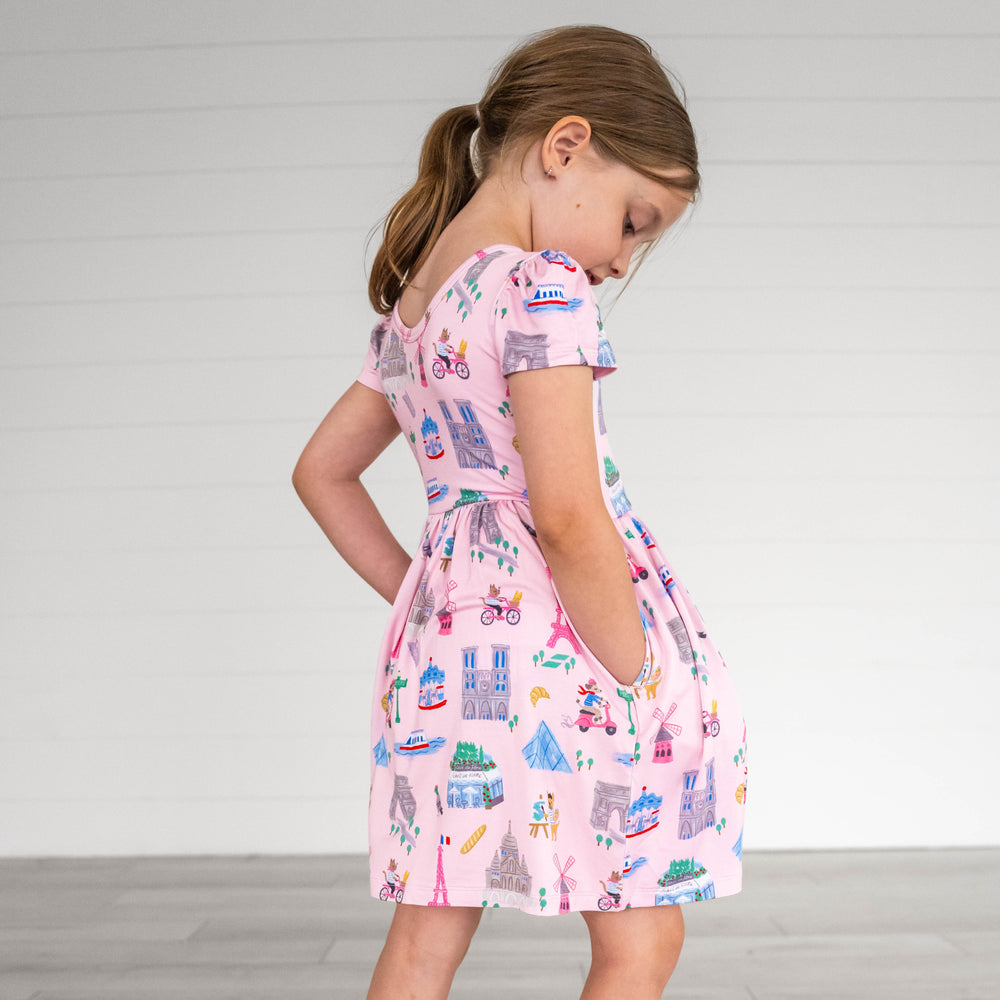 Side view image of girl wearing the Pink Weekend in Paris Skater Dress, with hands in pockets