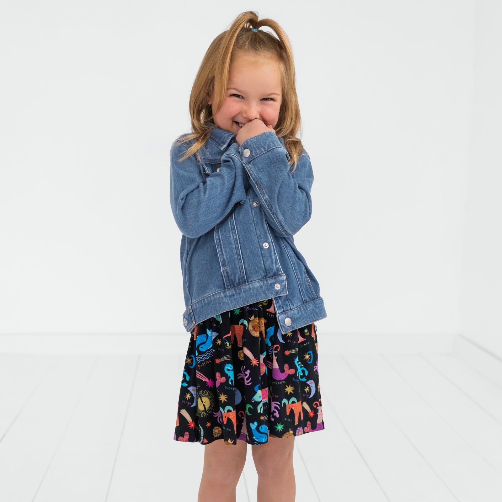 laughing child wearing a star signs skater dress and midwash blue denim trucker jacket