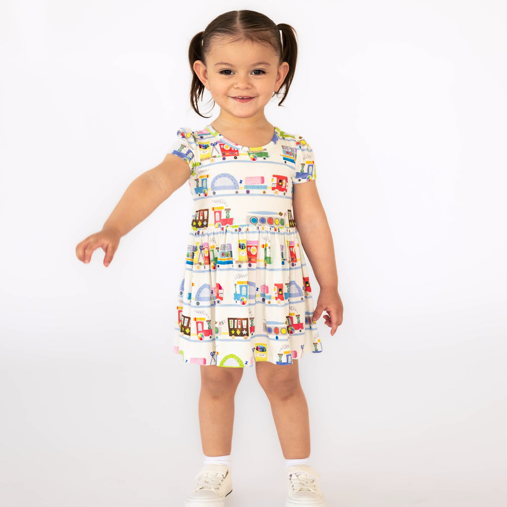 Girl standing while wearing the Education Express Skater Dress with Bodysuit