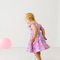 Profile view of a child playing wearing a Magical Birthday flutter twirl dress with bodysuit