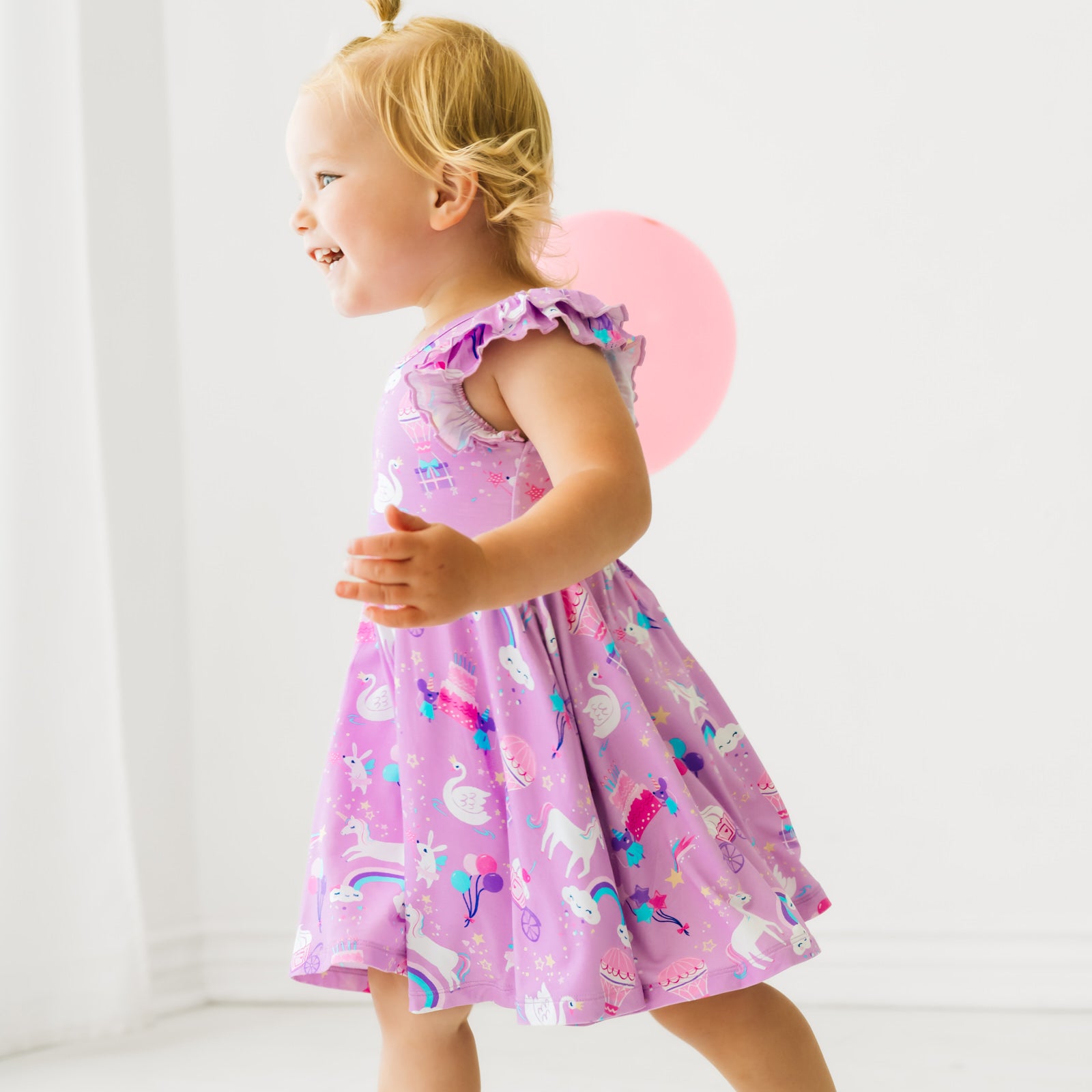 Alternate profile view of a child playing wearing a Magical Birthday flutter twirl dress with bodysuit