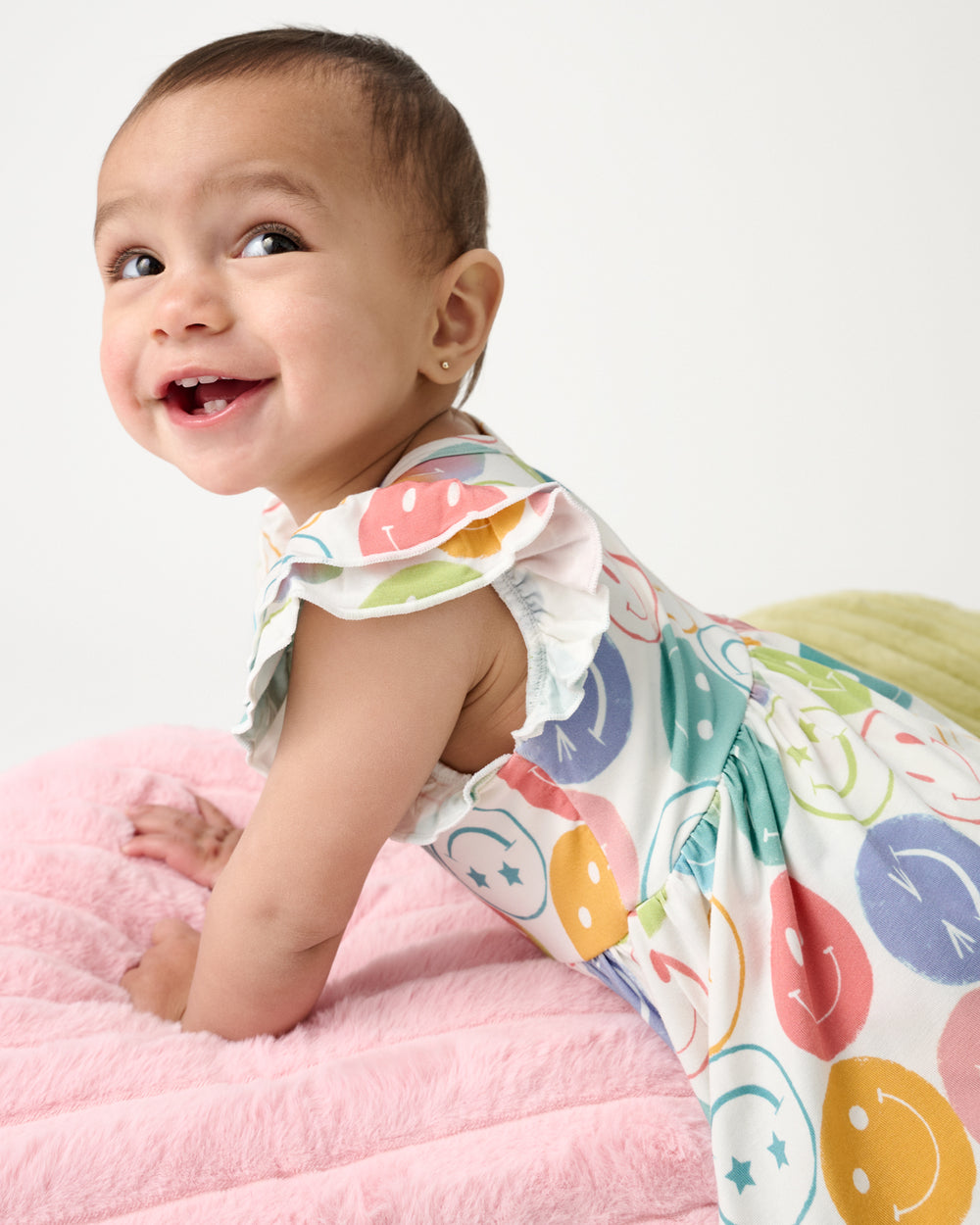 Baby laying on a pink plush pillow wearing the Positive Vibes Flutter Twirl Dress with Bodysuit