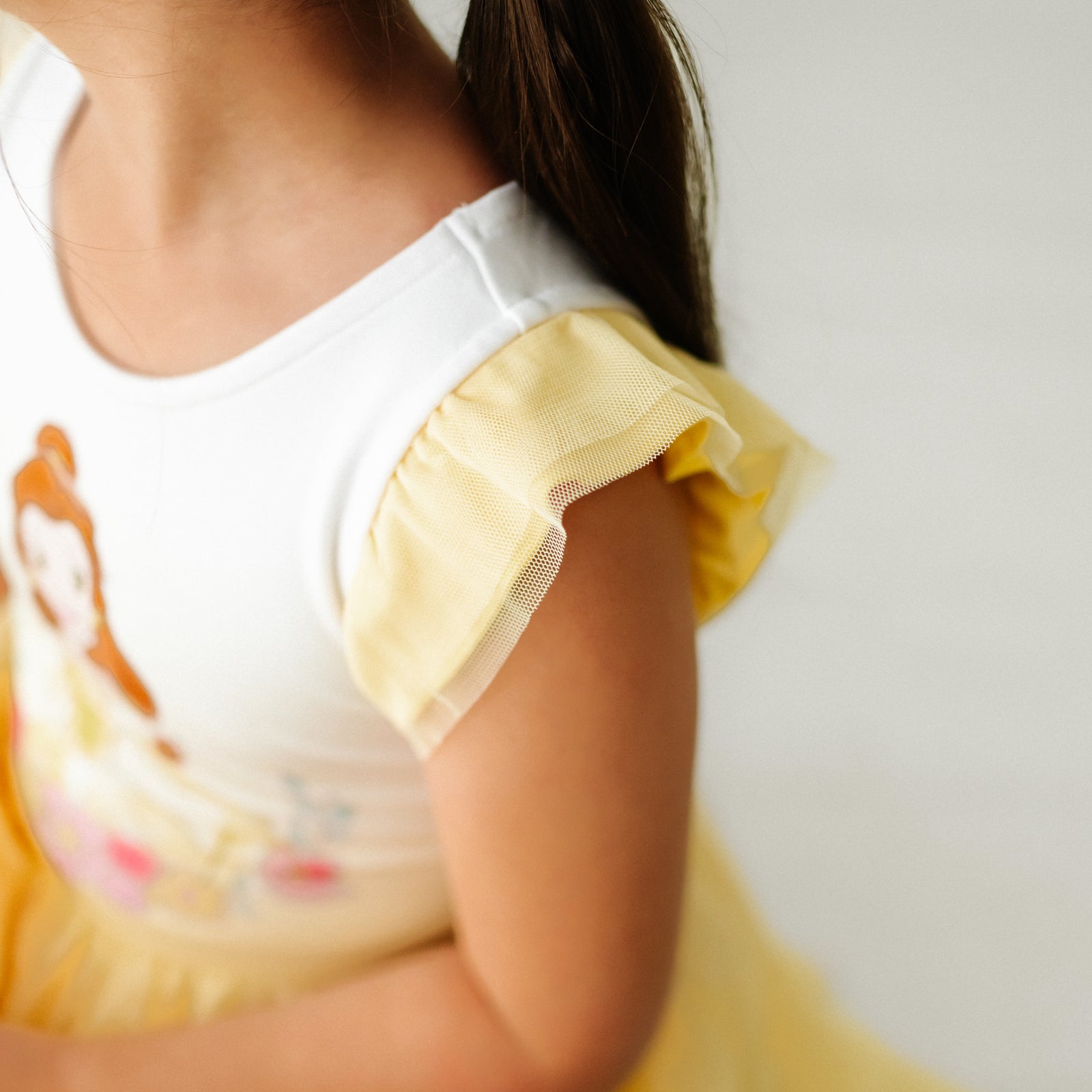 Close up image of a child wearing a Belle flutter tiered tutu dress, detailing the flutter sleeve