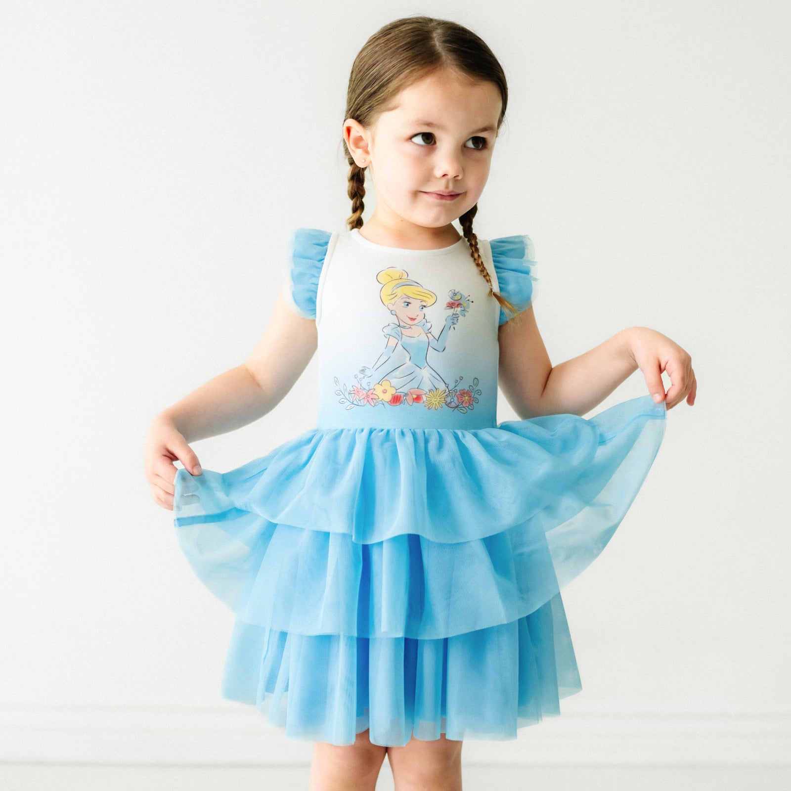 Child wearing a Cinderella flutter tiered tutu dress, holding out the sides of the dress