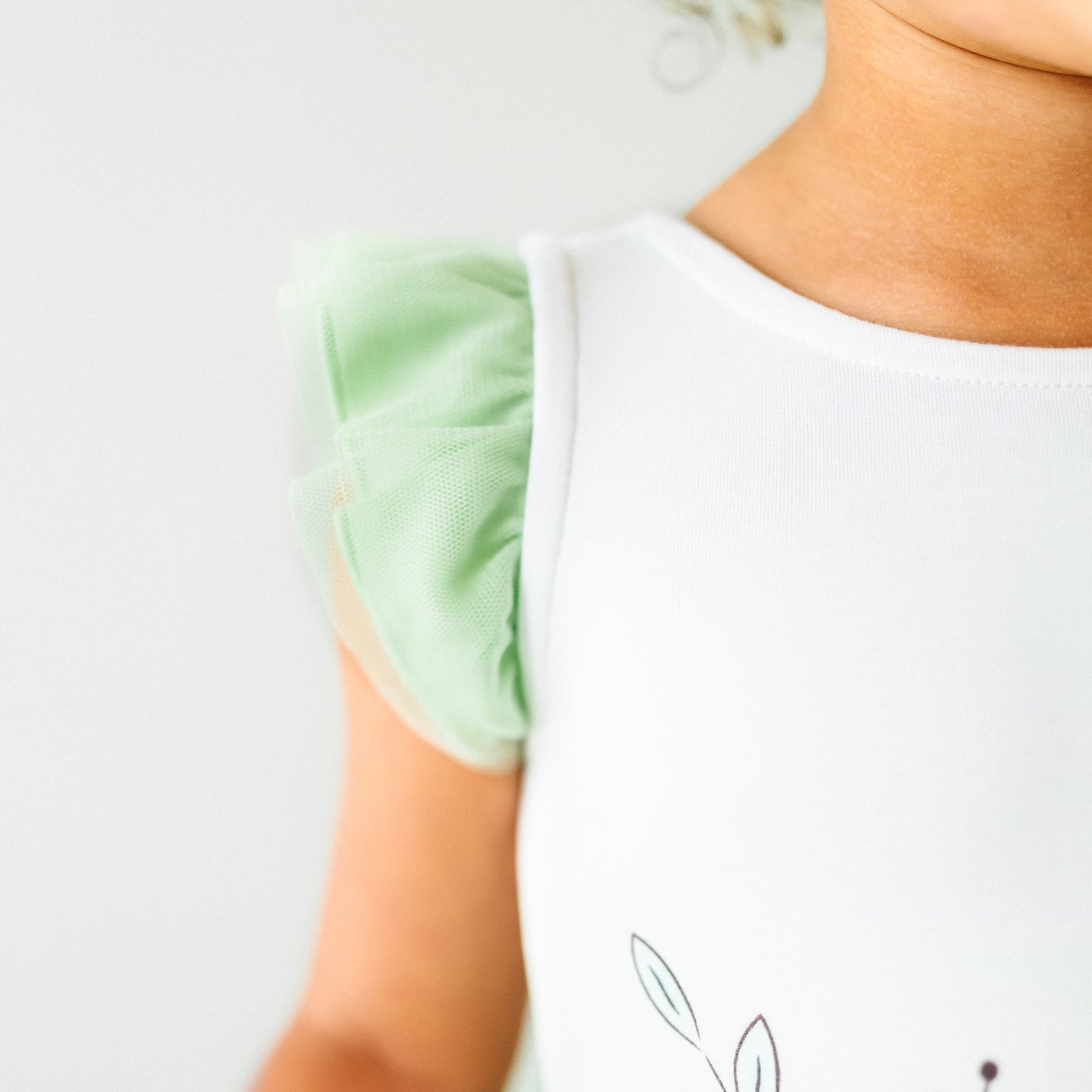 Close up image of a child wearing a Tiana flutter tiered tutu dress, detailing the flutter sleeve