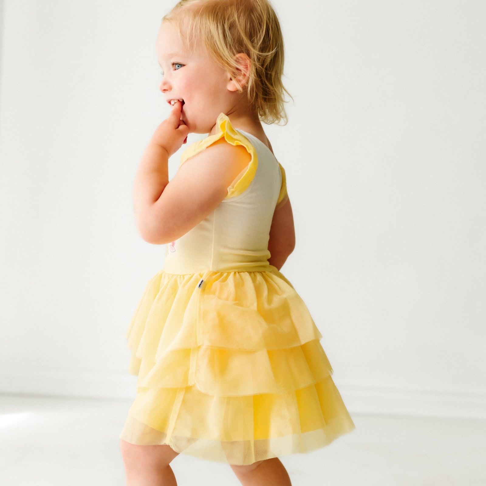 Side view image of a child wearing a Belle flutter tiered tutu dress with bloomer