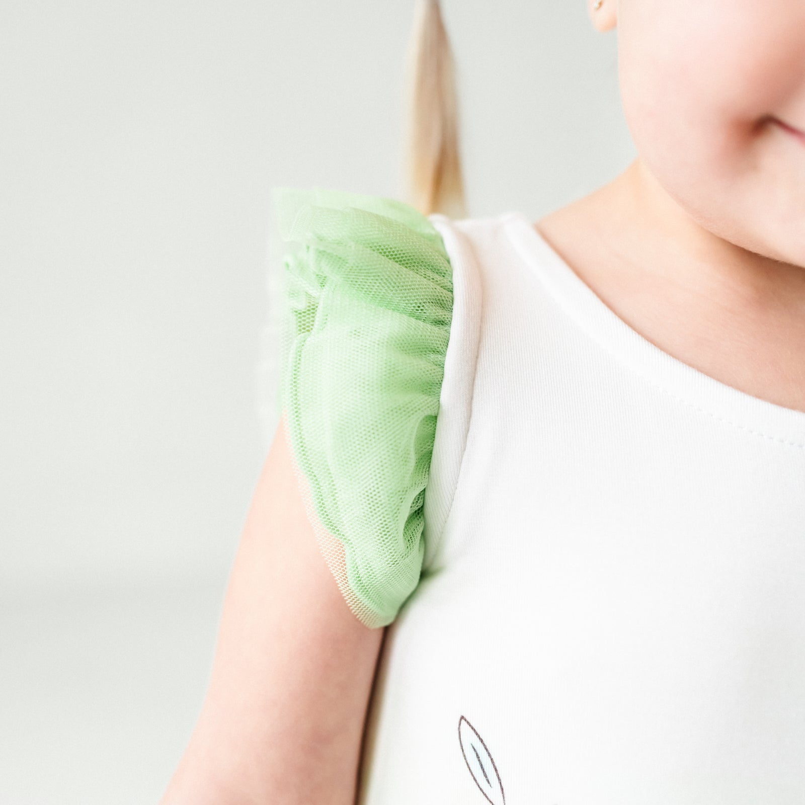 Close up image of a child wearing a Tiana flutter tiered tutu dress with bloomer, detailing the flutter sleeve
