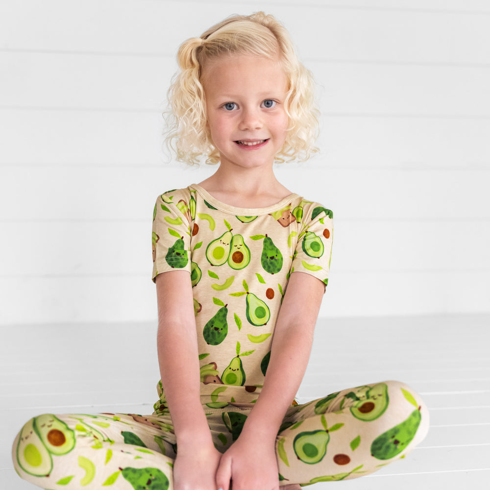 Image of a child sitting wearing an Avocado Toast two piece short sleeve pj set