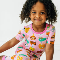 Close up image of a child sitting wearing Pink Party Pals two piece short sleeve pj set