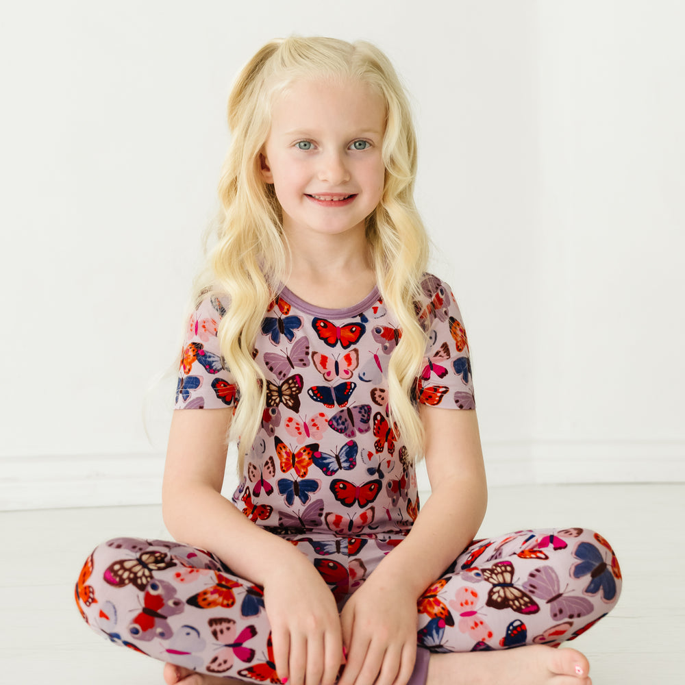 Child sitting on the ground wearing a Butterfly Kisses two-piece short sleeve pajama set