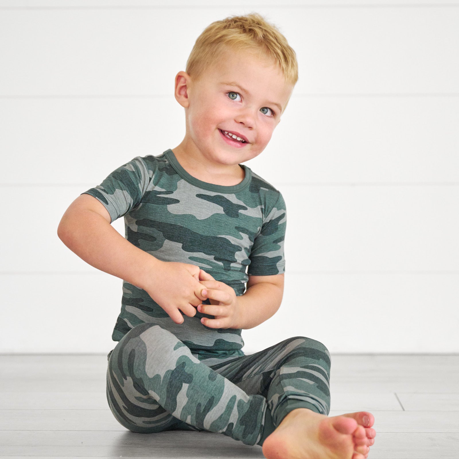 Boy sitting while in the Vintage Camo Two-Piece Short Sleeve Pajama Set