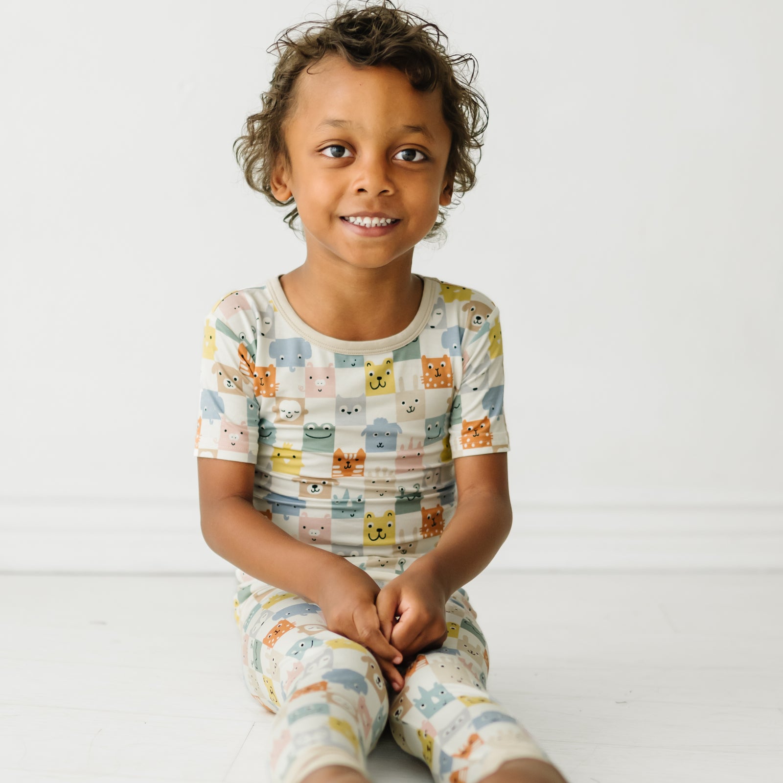 Child sitting wearing a Check Mates two piece short sleeve pajama set