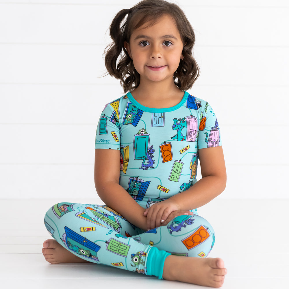 Girl sitting while wearing the Disney Monsters, Inc. Scream Team Short Sleeve Two-Piece Pajama Set