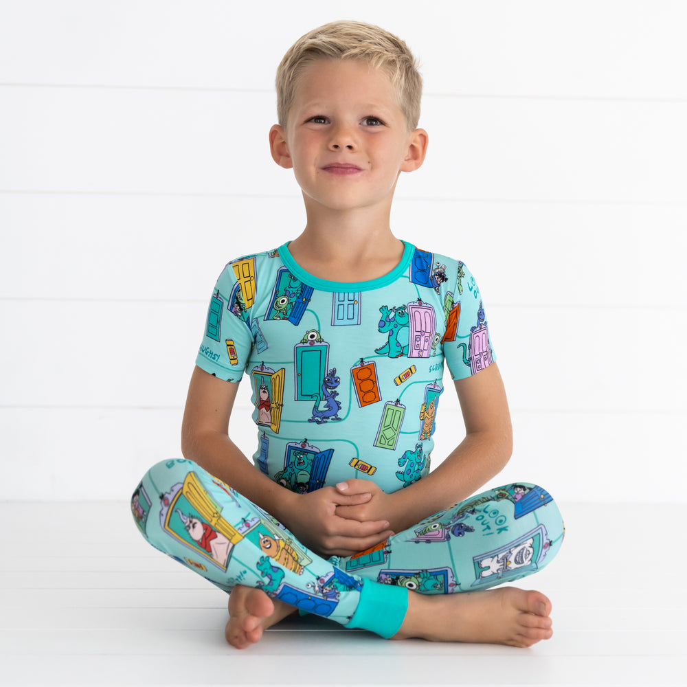 Boy sitting while in the Disney Monsters, Inc. Scream Team Short Sleeve Two-Piece Pajama Set