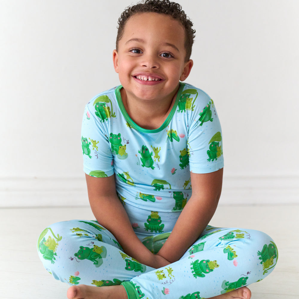 Child sitting on the ground wearing a Leaping Love two-piece short sleeve pajama set