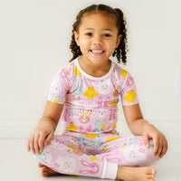 Child sitting wearing a Pink Pastel Parade two piece short sleeve pajama set