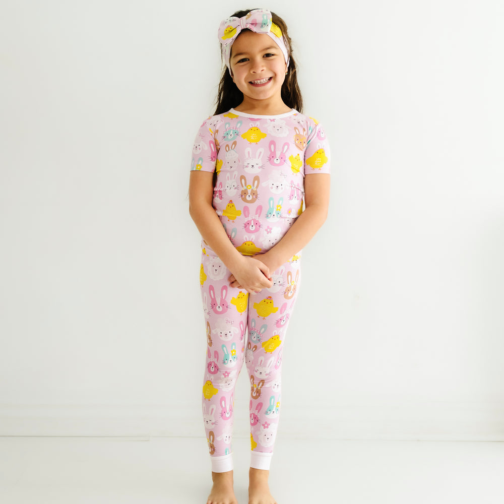 Click to see full screen - Child wearing a Pink Pastel Parade two piece short sleeve pajama set paired with a matching luxe bow headband