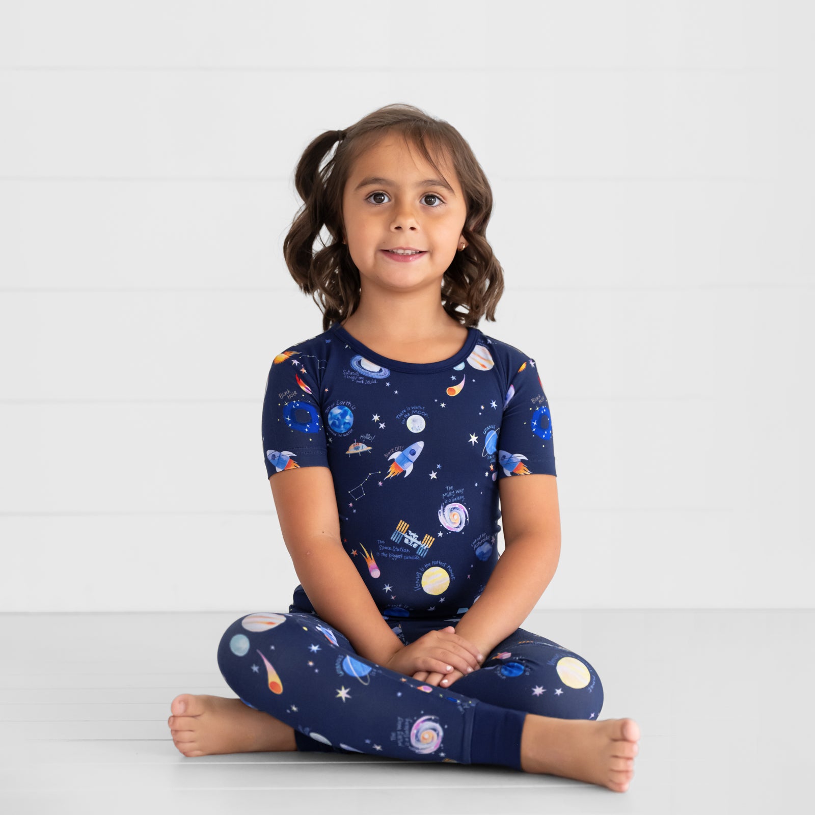 Image of a child sitting and posing wearing a Through My Telescope two piece short sleeve pj set