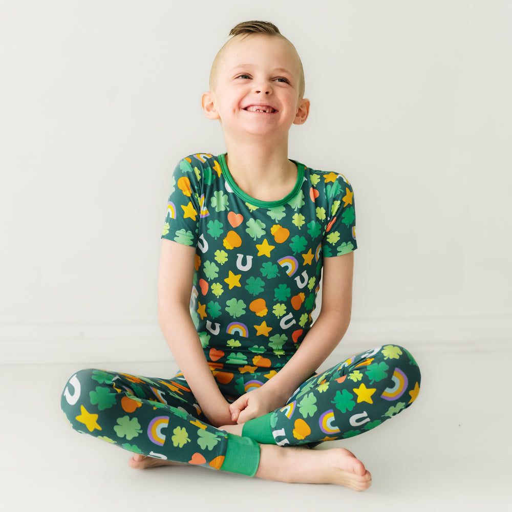 Click to see full screen - Child sitting wearing a Lucky printed two piece short sleeve pajama set